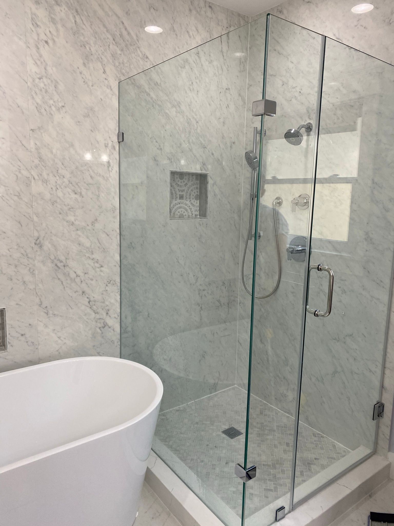 A bathroom with a bathtub and a walk in shower with a glass door.