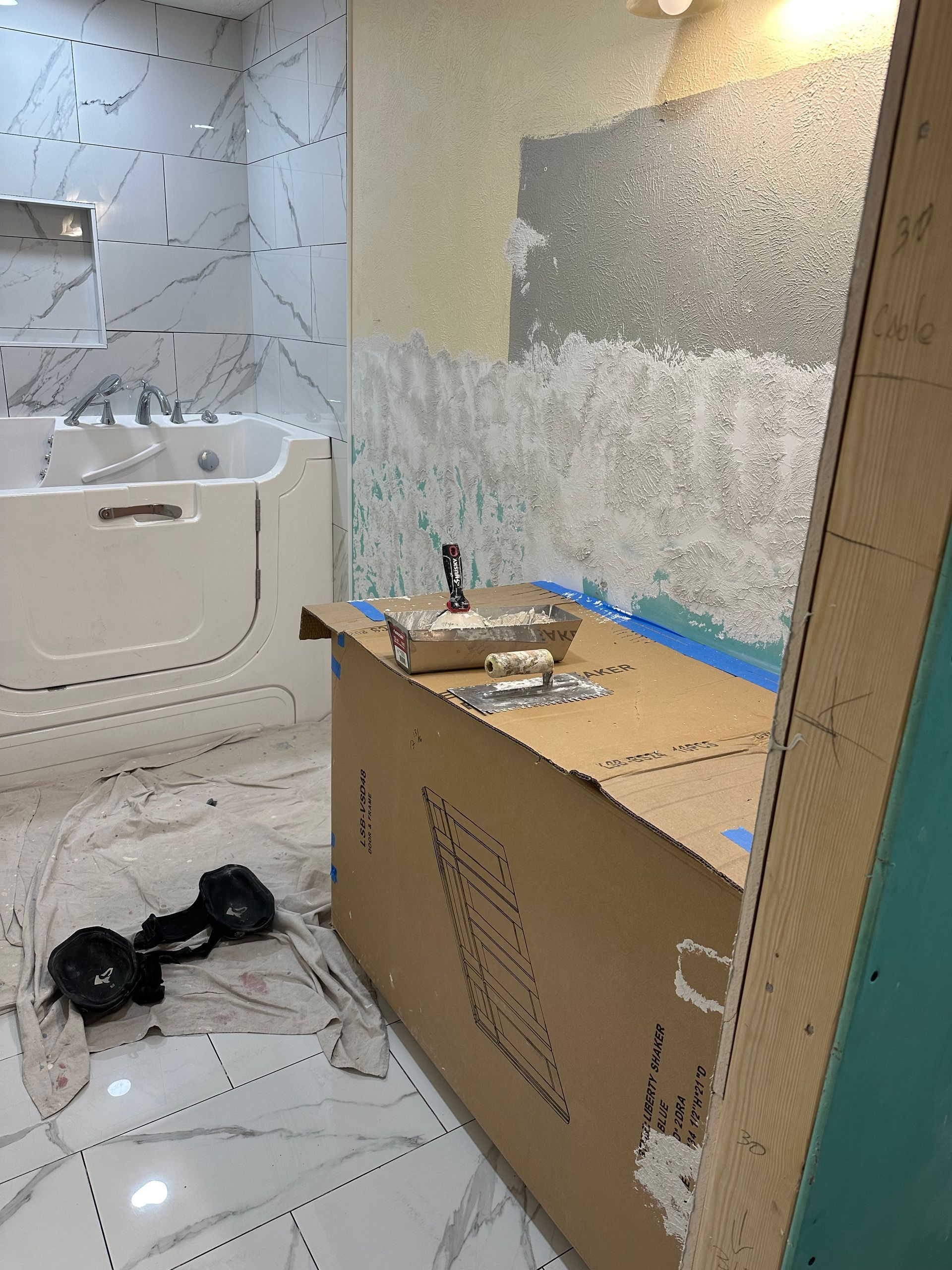 A bathroom with a walk in tub and a cardboard box on the floor.