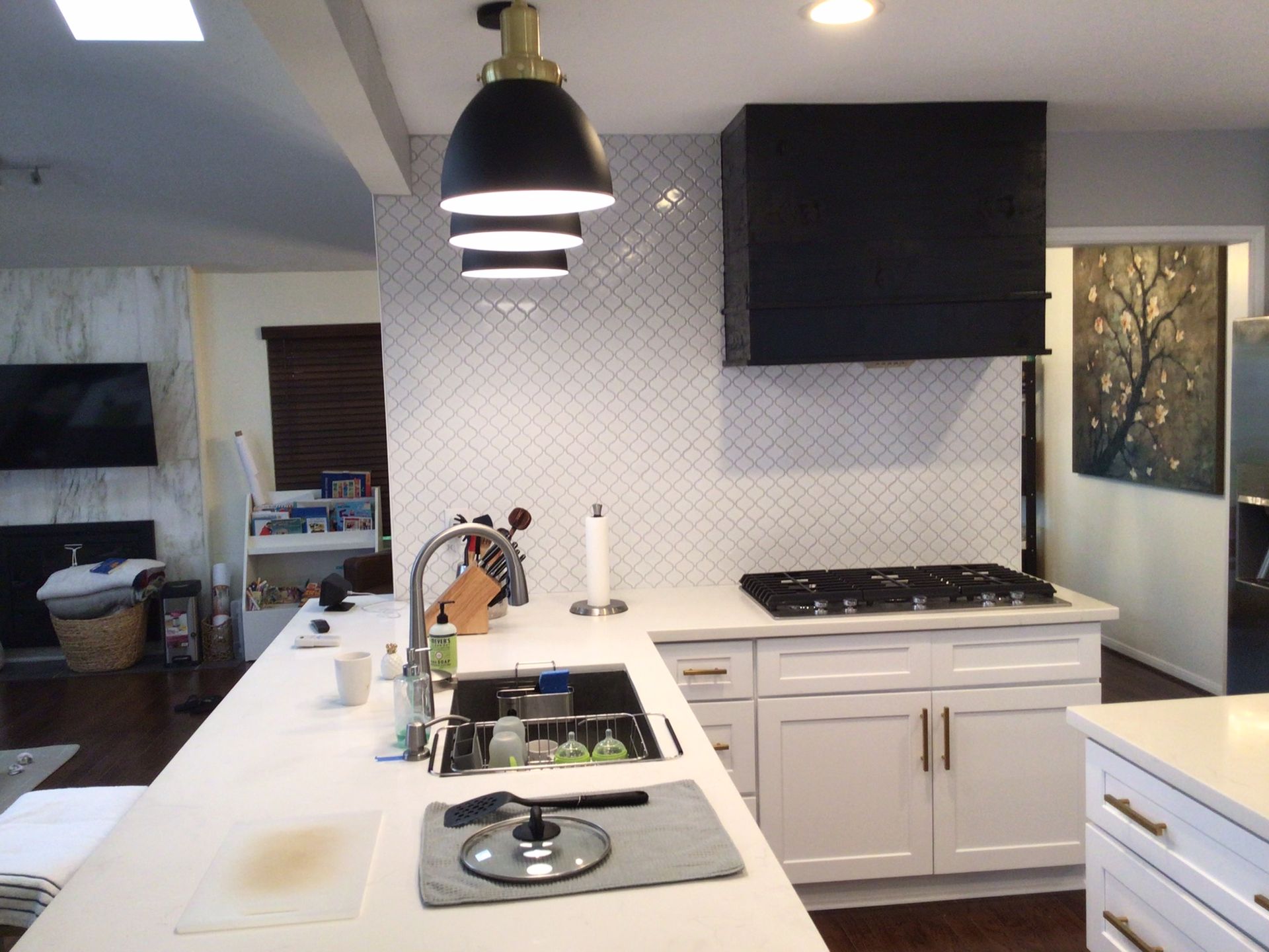 A kitchen with white cabinets and a black hood