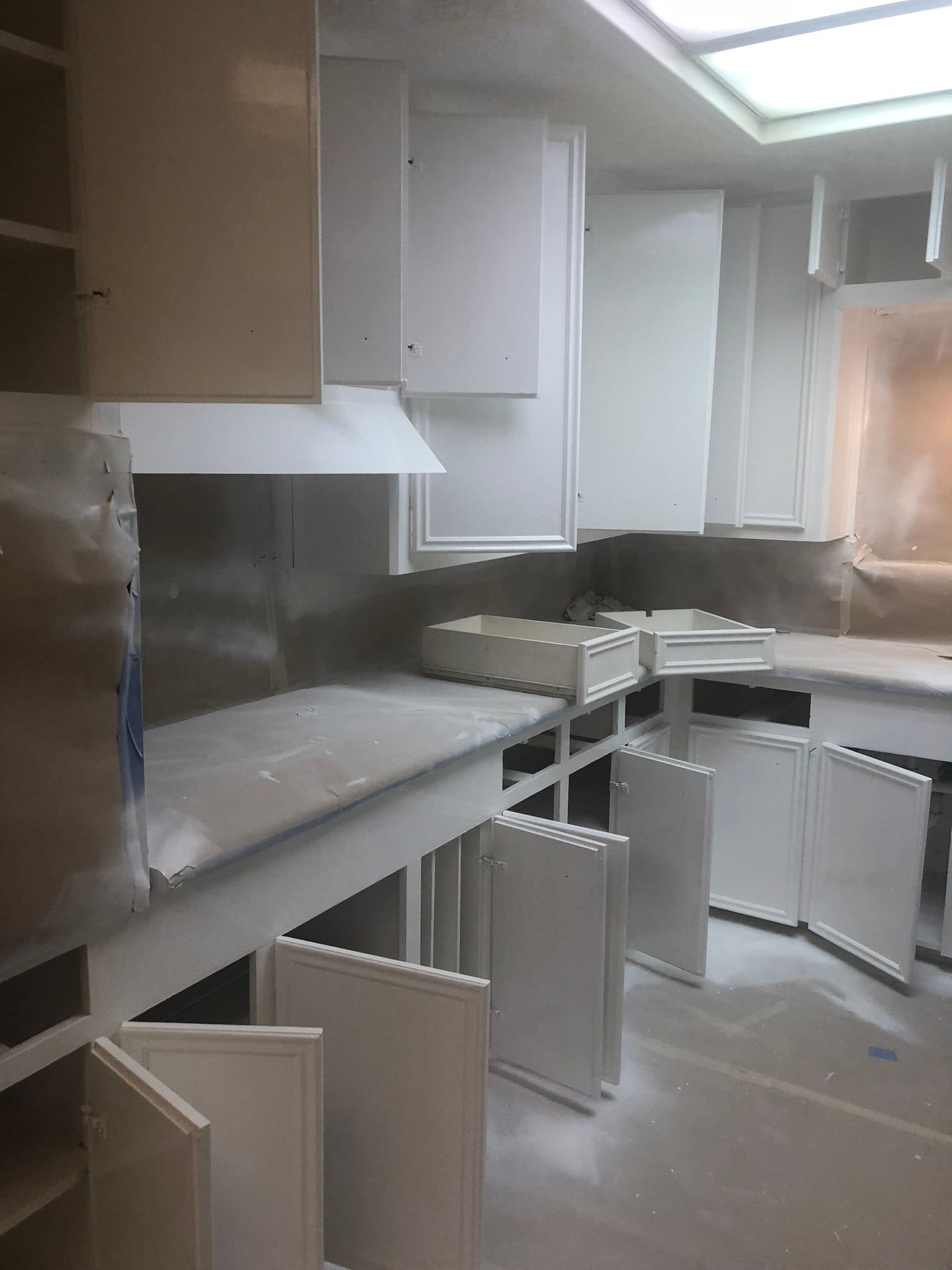 A kitchen with white cabinets and counter tops is being painted.